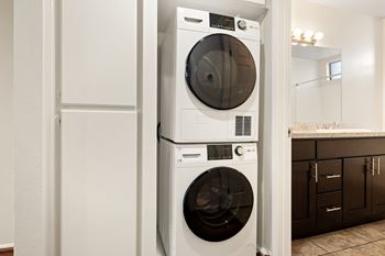 A white front loading washing machine is stacked on top of another white front loading washing machine.